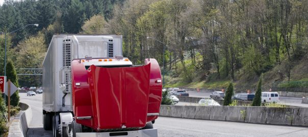 Broken on the road red semi truck with an open hood